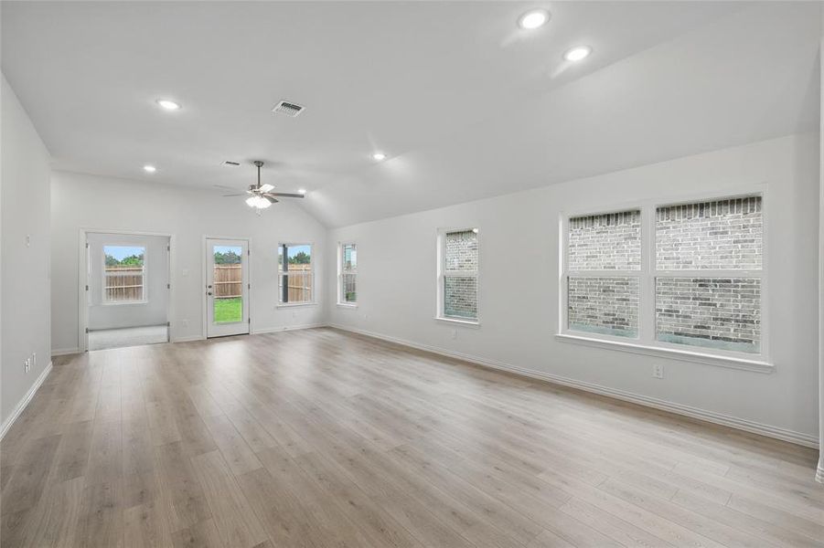 Unfurnished living room with a ceiling fan, lofted ceiling, light wood finished floors, and recessed lighting