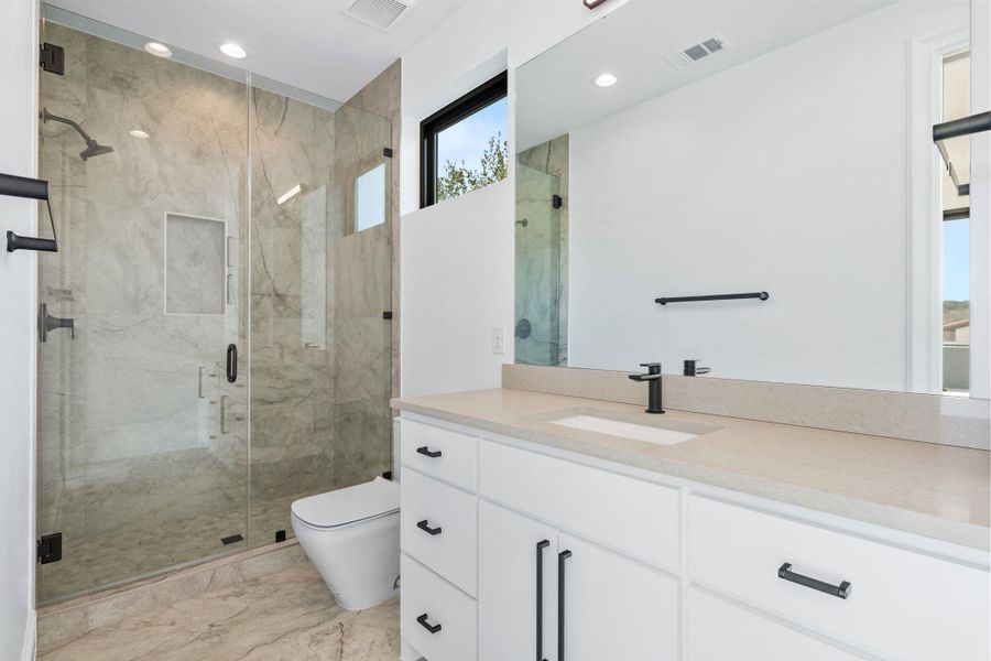 Bathroom featuring a marble finish shower, vanity, and recessed lighting