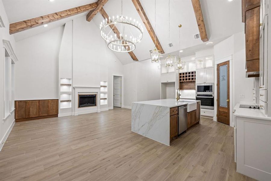 Vaulted ceiling great room featuring exposed wood beams and wood-finish flooring Vaulted ceiling great room featuring exposed wood beams and wood-finish flooring