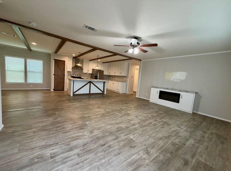 Expansive open-concept living space featuring wood-finish flooring and exposed beam ceilings