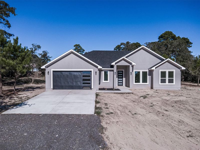 View of front facade featuring concrete driveway, a garage, and stucco siding
