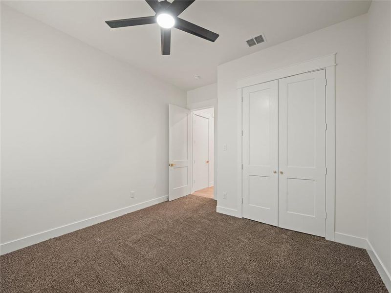 Unfurnished bedroom featuring dark colored carpet, a closet, and ceiling fan