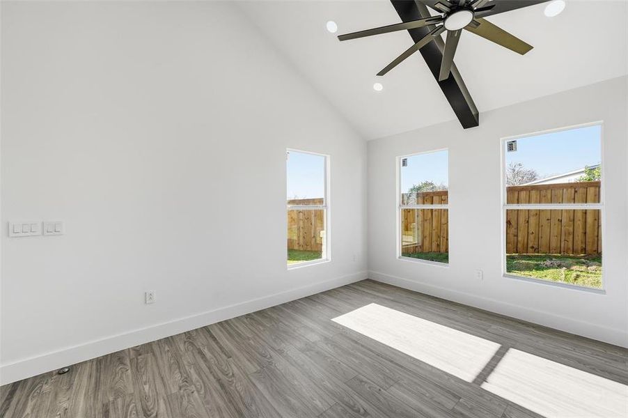 Spare room featuring wood finished floors, high vaulted ceiling, ceiling fan, and recessed lighting Spare room featuring wood finished floors, high vaulted ceiling, ceiling fan, and recessed lighting