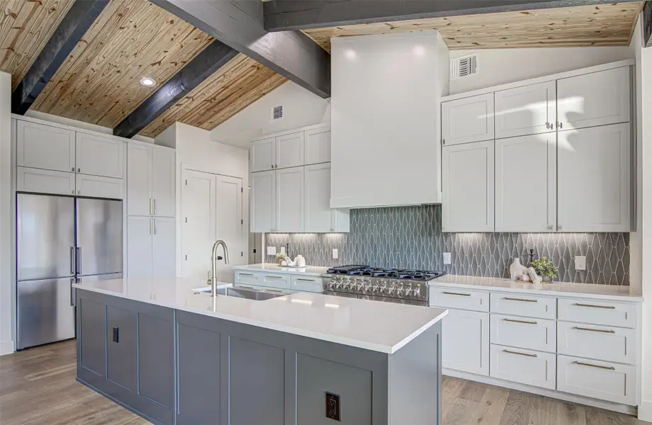 Kitchen with high quality appliances, a sink, light countertops, white cabinetry, and light wood-style flooring Kitchen with high quality appliances, a sink, light countertops, white cabinetry, and light wood-style flooring