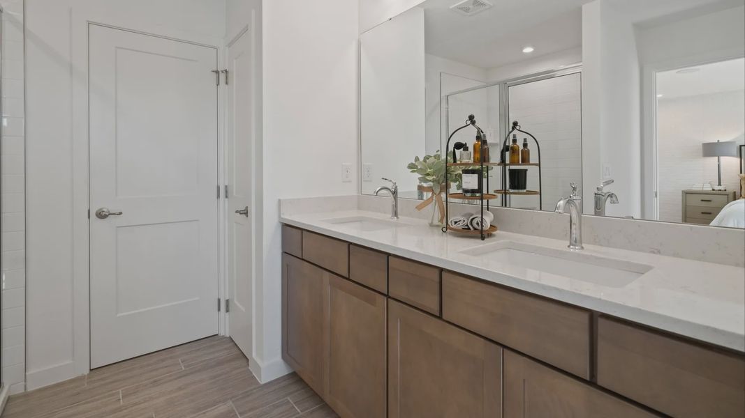 Primary  bath with dual sink vanity and private water closet in a DRB Home Clementine model at the Trinity Place community.