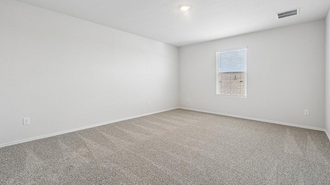 An inviting room offering soft carpeting and natural light through the window, providing a comfortable setting.