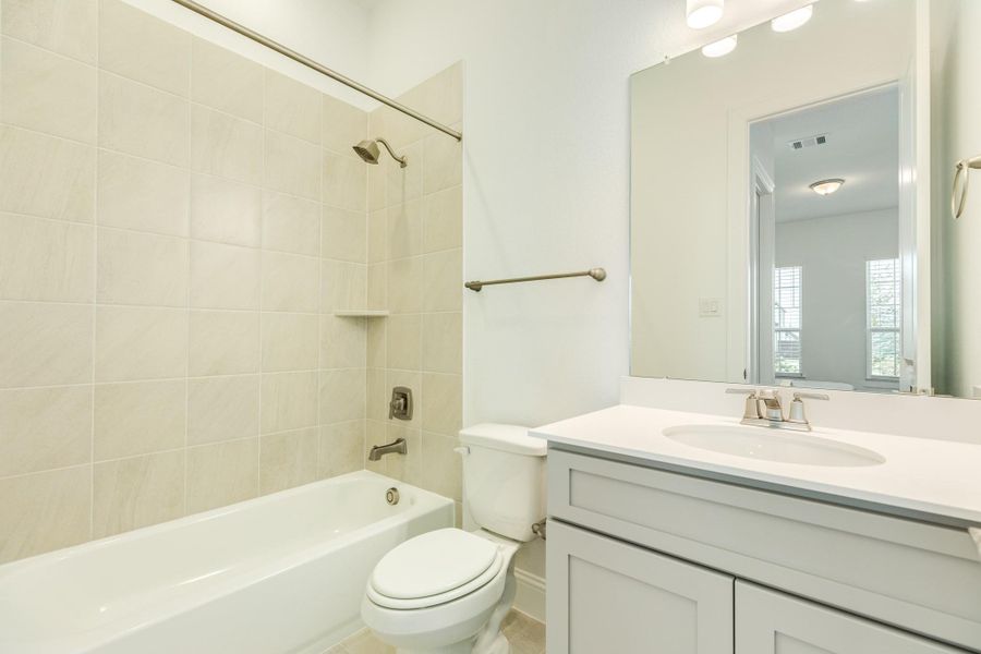 Stunning ensuite primary bath featuring elegant tile flooring, a spacious shower/tub combination, sleek granite countertops, and an abundance of natural light.When writing descriptions for real estate photography, it is beneficial to highlight high-end finishes and functional features that appeal to potential buyers. Descriptions should be concise, professional, and evocative to help the viewer visualize