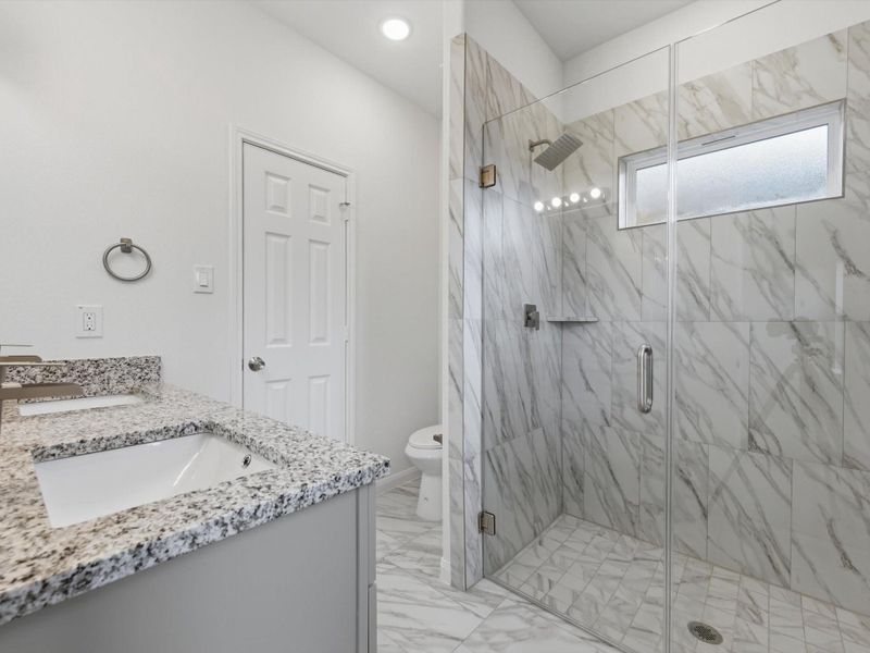 Thoughtfully finished, the primary bath offers dual vanities, a sleek glass shower, and a generous walk-in closet.