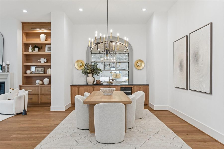 Warm oak cabinetry and soft gold sconces create a refined dining alcove, anchored by an arched mirror that introduces architectural depth. The space feels intimate yet connected to the home’s broader entertaining areas. *Previous Project*