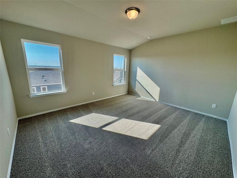 Carpeted spare room with baseboards and lofted ceiling