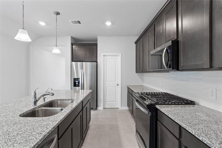 Discover this chef-ready kitchen featuring sleek, Barnett Slate shaker style cabinetry, white sparkle granite countertops, and a full suite of stainless steel appliances, including an over-the-range microwave and a side-by-side refrigerator.