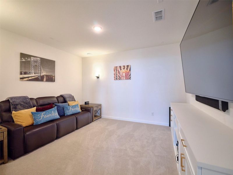 Step into this inviting media room featuring plush carpet, sleek sconces, and elegant designer cabinetry.