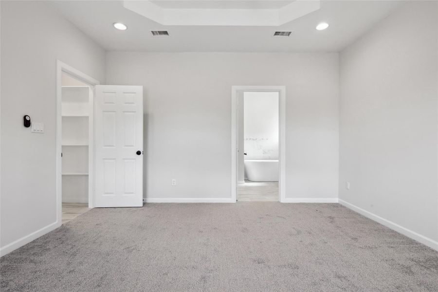 Unfurnished bedroom featuring carpet, recessed lighting, baseboards, ensuite bathroom, and a tray ceiling Unfurnished bedroom featuring carpet, recessed lighting, baseboards, ensuite bathroom, and a tray ceiling