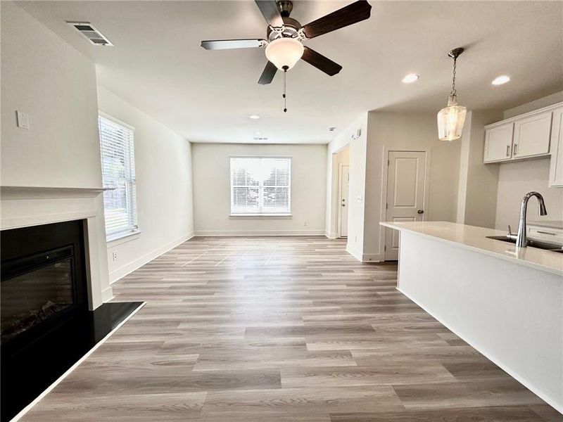 Kitchen with sink, hanging light fixtures, light hardwood / wood-style floors, ceiling fan, and white cabinets