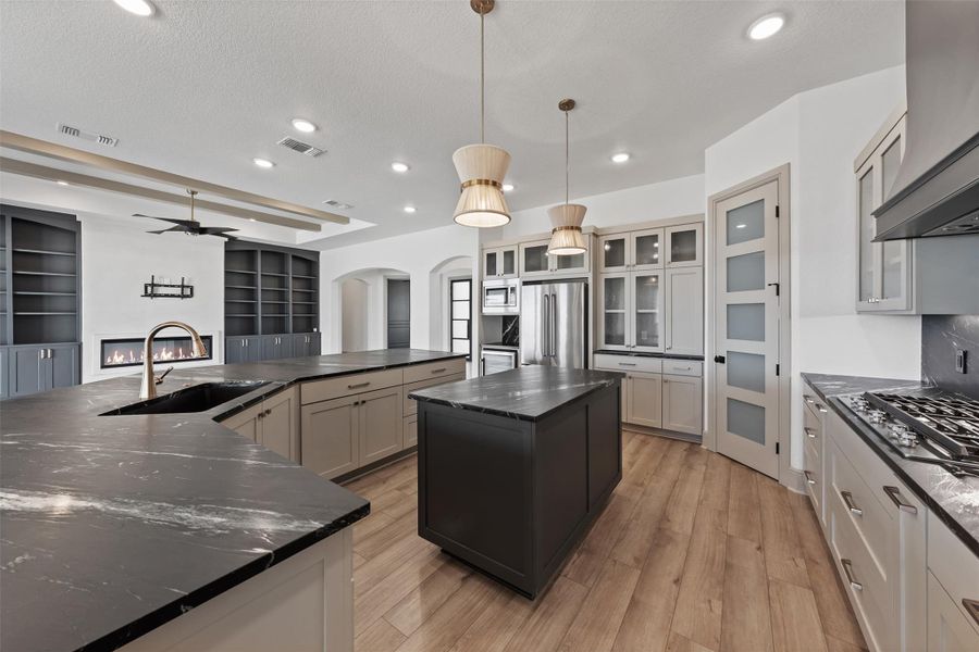 Kitchen featuring visible vents, arched walkways, a large island with sink, a sink, and appliances with stainless steel finishes