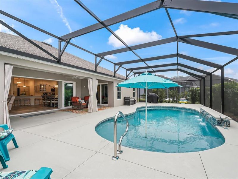 Pool area with expanded patio space, shallow shelf with umbrella, and three waterfalls