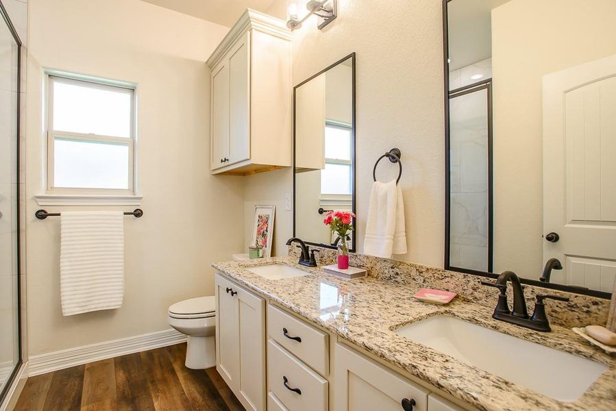 Bathroom featuring plenty of natural light, an enclosed shower, double vanity, and wood finished floors Bathroom featuring plenty of natural light, an enclosed shower, double vanity, and wood finished floors