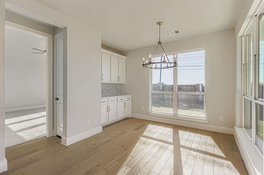 Unfurnished dining area with a chandelier and light wood-type flooring