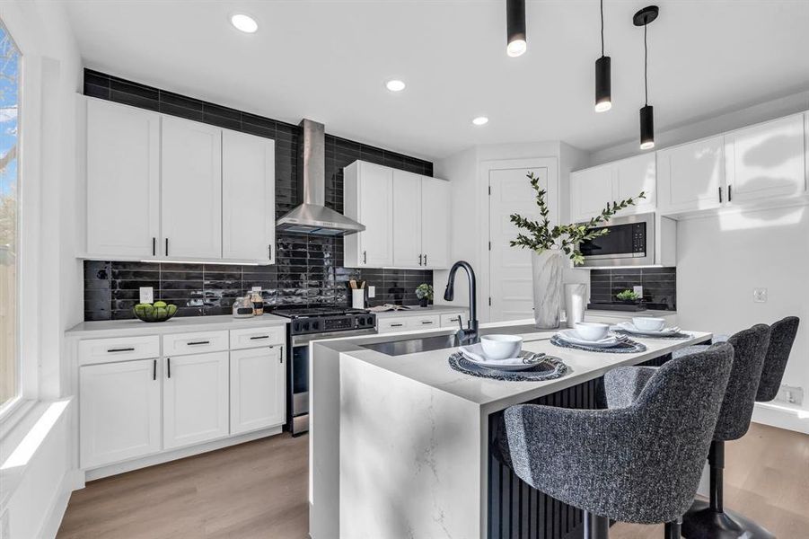 Kitchen with white cabinetry, a kitchen island with sink, wall chimney range hood, and appliances with stainless steel finishes