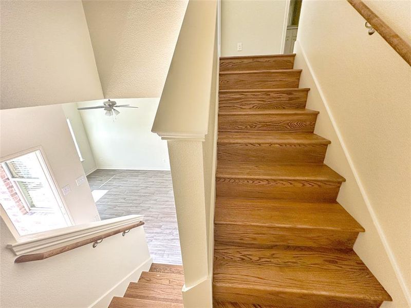 Stairs featuring wood finished floors, ceiling fan, and a textured wall