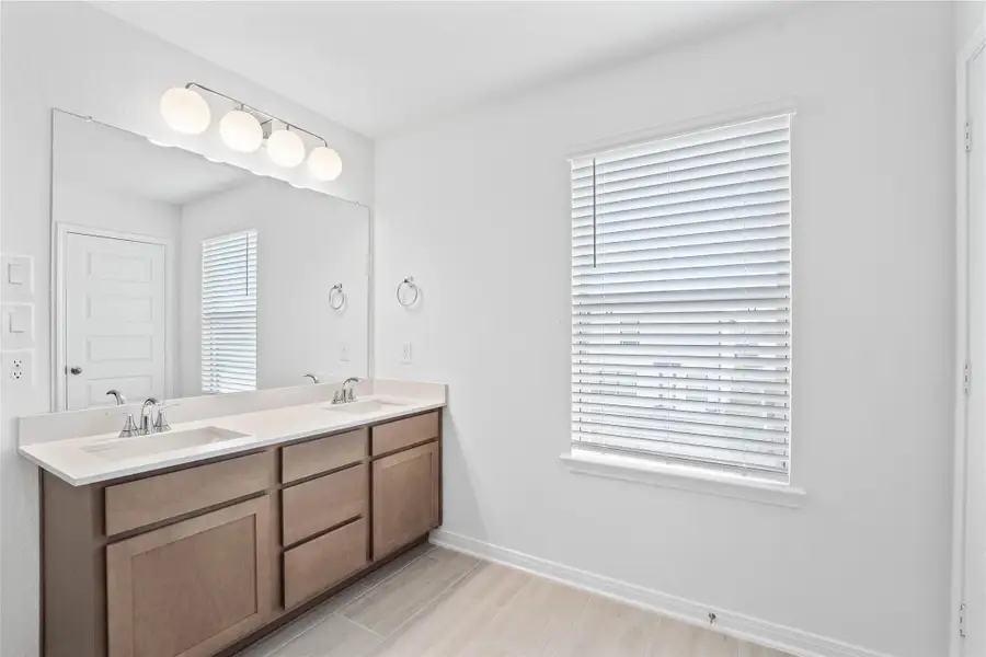 This beautifully updated primary bathroom provides plenty of room to share! Pictured here is the stained cabinetry paired with light countertops, dual vanity sinks, a large mirror, large window with blinds, high ceilings, custom paint, and stylish modern finishes throughout. This beautifully updated primary bathroom provides plenty of room to share! Pictured here is the stained cabinetry paired with light countertops, dual vanity sinks, a large mirror, large window with blinds, high ceilings, custom paint, and stylish modern finishes throughout.