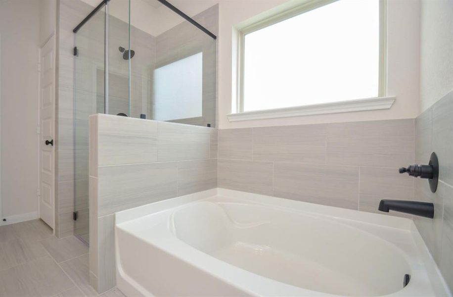 Unwind in the elegant soaking tub, surrounded by sophisticated tile work and complemented by a large window that fills the space with natural light. This relaxing sanctuary invites you to indulge in a spa-like experience from the comfort of home.