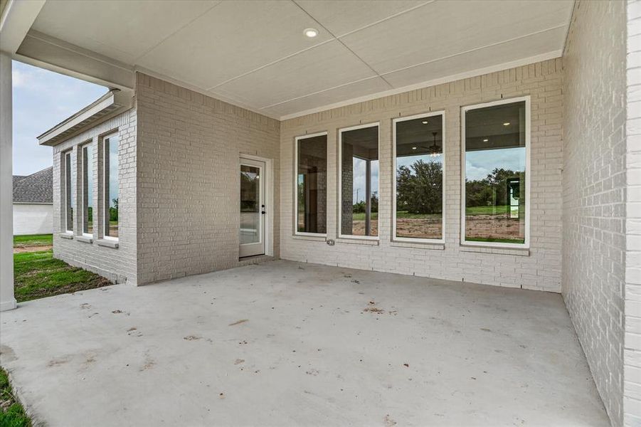 Covered patio with a concrete slab, recessed ceiling lighting, and light-colored brick exterior