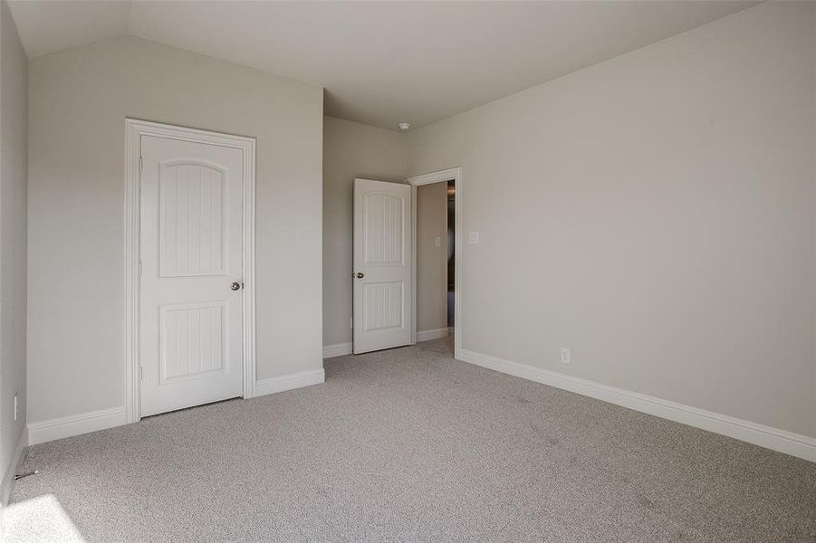 Unfurnished bedroom with lofted ceiling and carpet