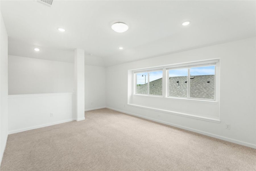 Empty room with white walls, beige carpet, recessed lighting, and a large window