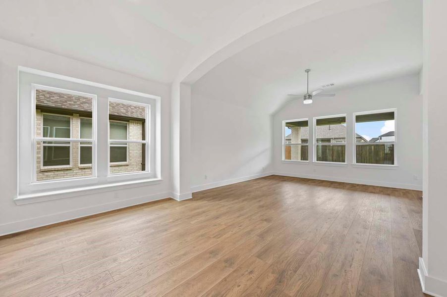Unfurnished living room with a ceiling fan, baseboards, wood-type flooring, and vaulted ceiling