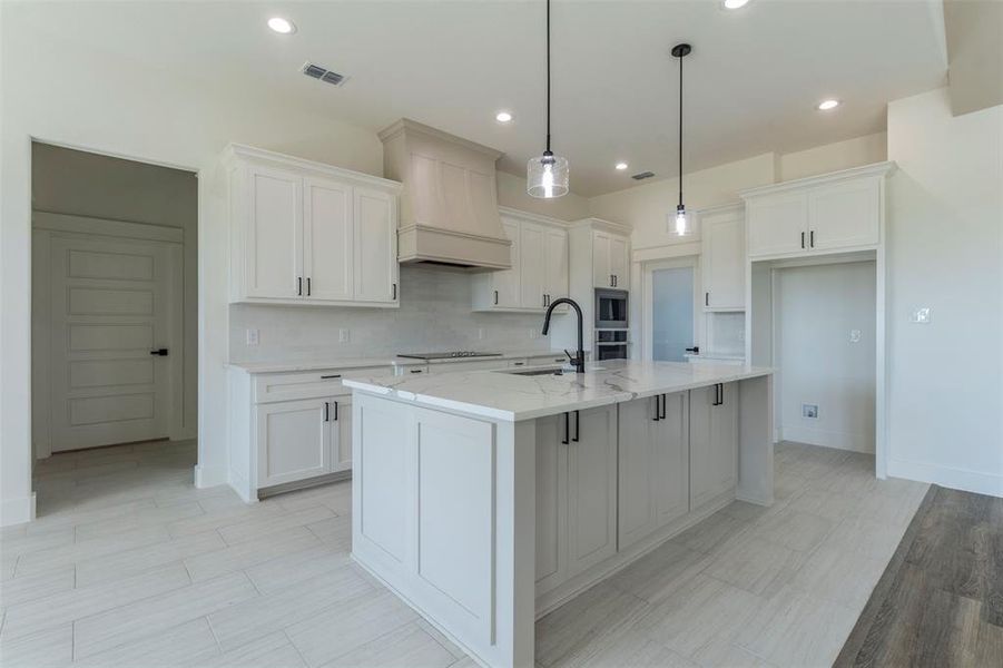 Kitchen featuring pendant lighting, white cabinetry, and a kitchen island with sink