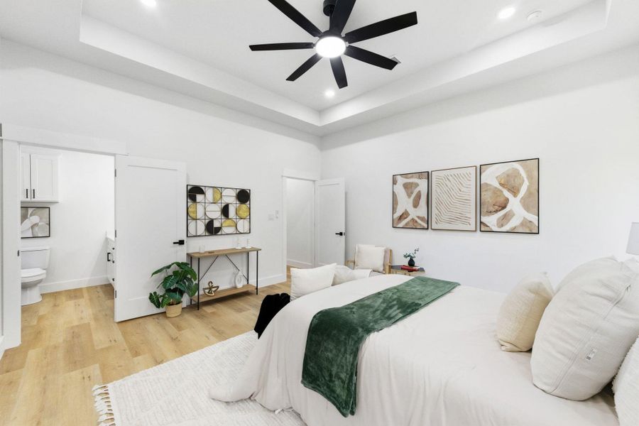 Bedroom with a tray ceiling, light wood-style floors, ceiling fan, and recessed lighting Bedroom with a tray ceiling, light wood-style floors, ceiling fan, and recessed lighting