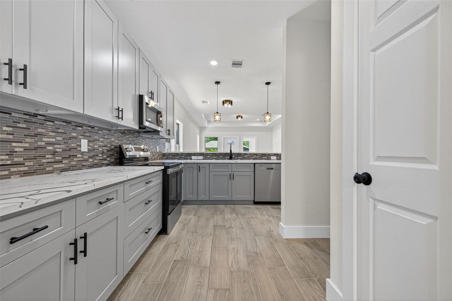 Equipped with stainless steel appliances and pendant lighting, it offers a spacious, contemporary feel with ample storage and workspace.