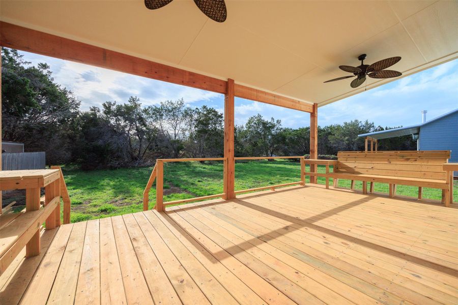 Wooden deck with dual ceiling fans and a yard