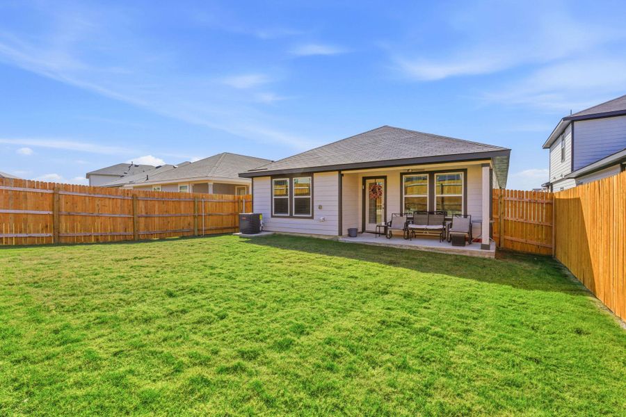 Back of house with a patio area, a fenced backyard, roof with shingles, and an outdoor living space