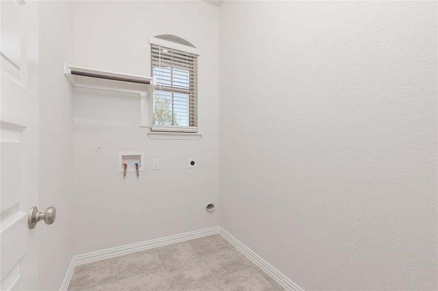 Laundry area with hookup for a gas dryer, hookup for an electric dryer, light tile patterned flooring, and washer hookup