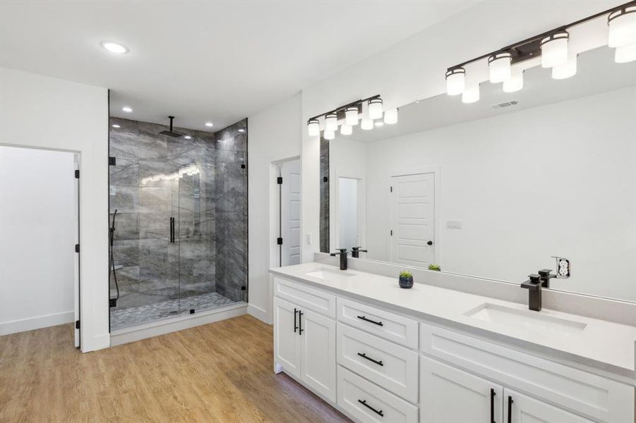 Bathroom featuring dual vanity, wood-type flooring, and an enclosed shower