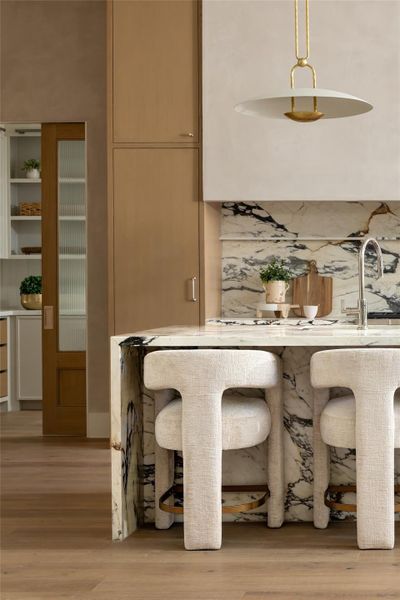 Calacatta marble countertops and backsplash, a pot filler, and a custom pocket reeded glass door. Calacatta marble countertops and backsplash, a pot filler, and a custom pocket reeded glass door.