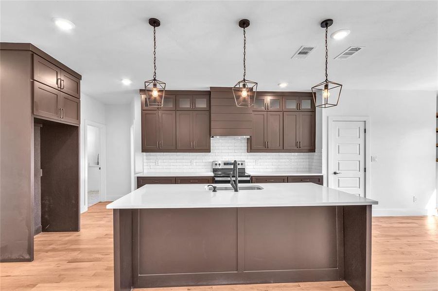 Kitchen featuring light hardwood / wood-style flooring, electric stove, a kitchen island with sink, and sink Kitchen featuring light hardwood / wood-style flooring, electric stove, a kitchen island with sink, and sink
