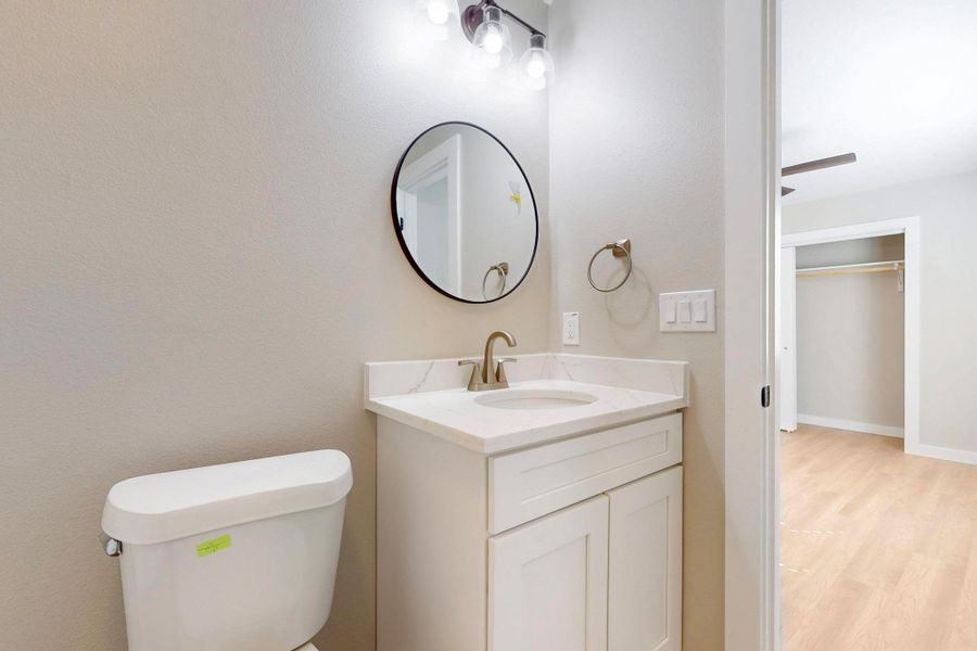 Primary bathroom featuring vanity, toilet, and wood like floors. New everything.