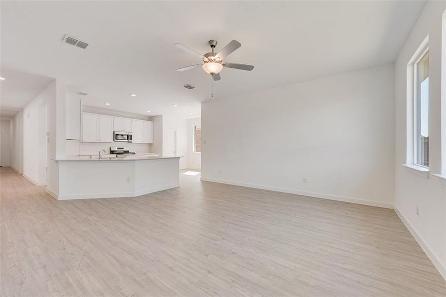 Unfurnished living room featuring ceiling fan, sink, and light hardwood / wood-style flooring