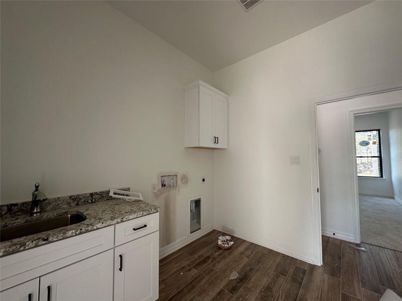 Laundry area with dark wood-style flooring, cabinet space, washer hookup, electric dryer hookup, and hookup for a gas dryer