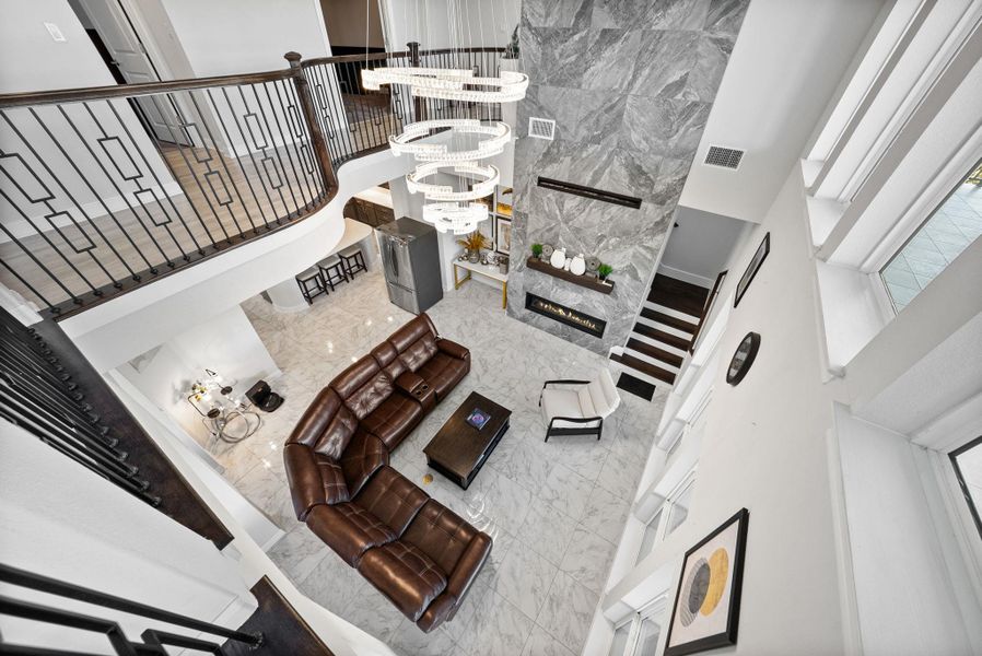 Living area featuring a high ceiling, light marble finish floors, suspended lighting, and a fireplace
