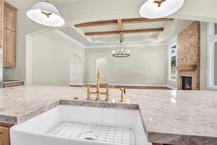 Kitchen featuring open floor plan, a stone fireplace, hanging light fixtures, beam ceiling, and coffered ceiling