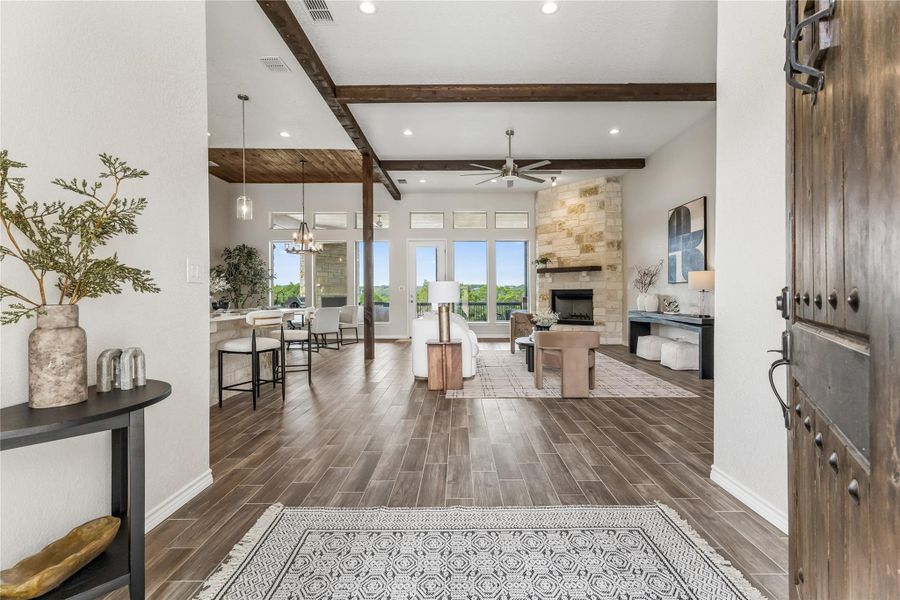 Natural light floods this inviting living space, highlighting the wood-look flooring and rustic beamed ceilings.