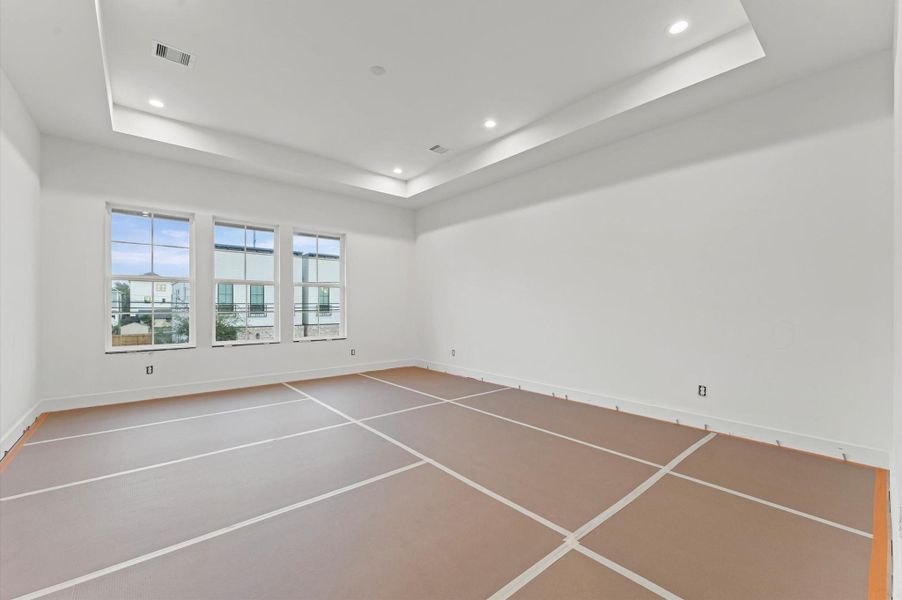 Primary bedroom with tray ceiling and abundant natural light.