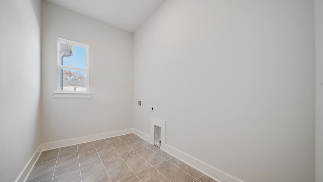 Dedicated laundry room with hookups, tile floor, and window
