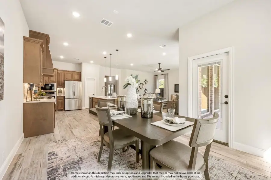 Open-concept dining area with dark wood table, light hardwood floors, and kitchen visible in background