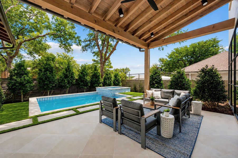 An inviting covered patio featuring robust timber beams overlooks a sparkling swimming pool.
