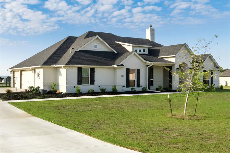 View of front of home with roof with shingles, a chimney, and a front lawn